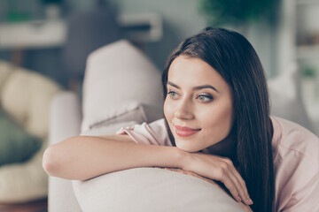 Photo portrait of adorable girl looking into distance thinking lying on hand on sofa indoors