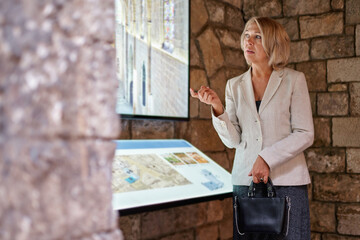woman at museum uses touchscreen monitor electronic guide, the concept of modern life