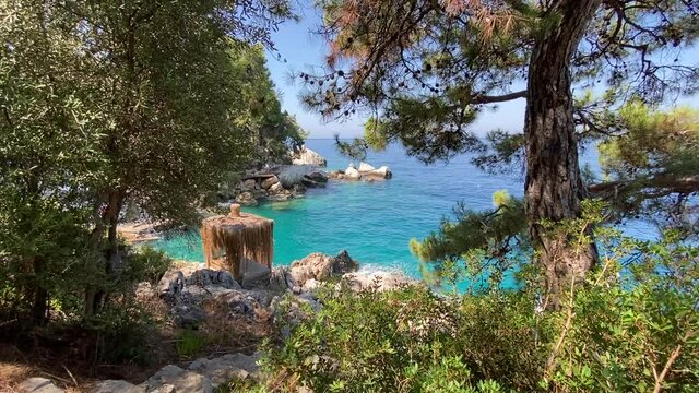 Turquoise Mediterranean Sea and rocky green island with pine trees. Beautiful clean blue sea water and skies, green trees and a boat on the water.