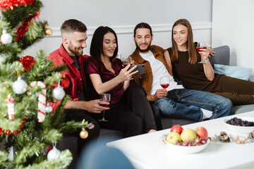 Image of multinational friends using mobile phone while drinking wine