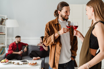 Image of joyful friends talking each other while drinking wine