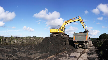 Obraz premium A crane filling a trailer with ripened dredging spoil from a storage compartment 