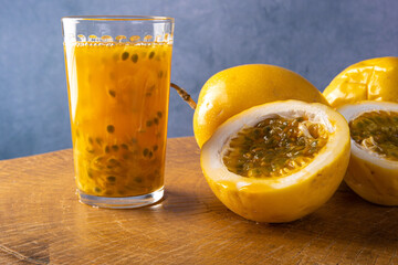 Passion fruit and a glass of juice on rustic wood, blue background, selective focus.