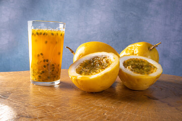 Passion fruit and a glass of juice on rustic wood, blue background, selective focus.