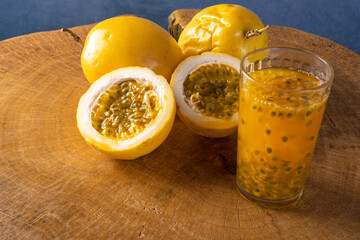 Passion fruit and a glass of juice on rustic wood, blue background, selective focus.
