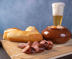 Breads, vinaigrette, sliced ​​roasted sausage and a glass of beer on a table, blue background, selective focus.