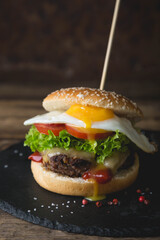 Hamburger with scrambled eggs on a dark background
