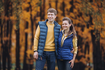 Portrait of a happy couple in autumn park, both looking in one direction