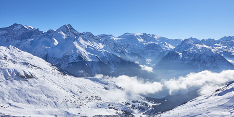 Panoramic view of the mountain valley with rare clouds near Tignes high-altitude ski resort in France during the winter season.