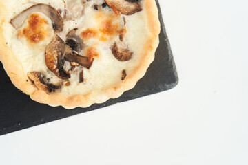 Tart with mushrooms and cheese on a white plate. Close-up