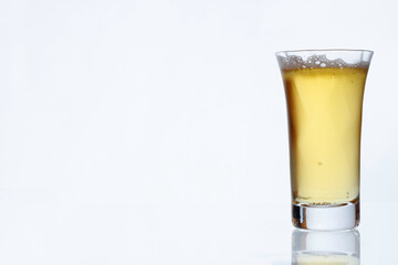 白い壁を背景に透明なグラスに入った冷えたビール