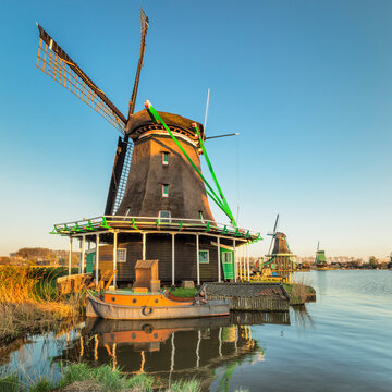Windmill and boat on Zaan River, open-air museum, Zaanse Schans, Zaandam, North Holland, Netherlands