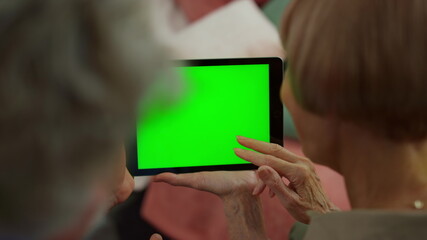 Overhead view senior woman and man hands using digital tablet with green screen