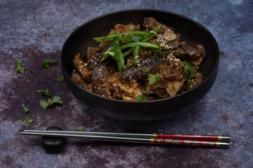 Korean vegan braised eggplant gaji namul  served in dark bowl