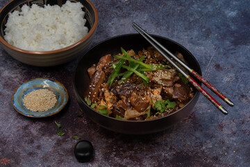 Korean vegan braised eggplant gaji namul  served in dark bowl  along with rice