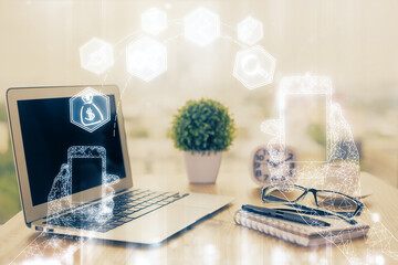 Computer on desktop in office with technology theme hologram. Double exposure. Tech concept.