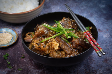 Korean vegan braised eggplant gaji namul  served in dark bowl  along with rice