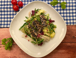 Grilled salmon fillets with sesame seeds, served over colorful mixed salad with balsamic dressing.