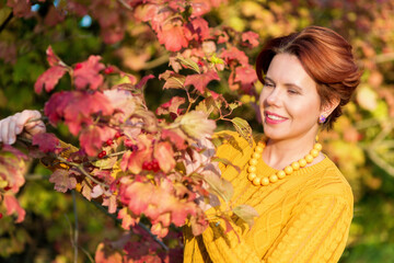 Naklejka premium Portrait of beautiful 30 year old woman standing near Red viburnum Bush