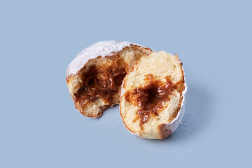 Two halves of sweet pastries, a doughnut with condensed milk. Isolated on a blue background. High-calorie food.