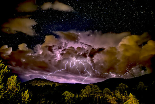 A storm approaching Sullivan Butte in Chino Valley at night with a starry sky above, Arizona