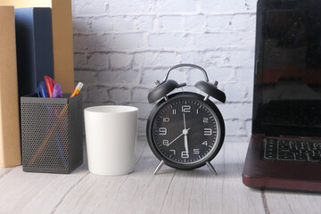 Naklejka premium stack of books , laptop and clock on table close up 