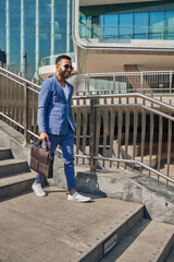 Smiling trendy Indian arabic business man walking in modern city