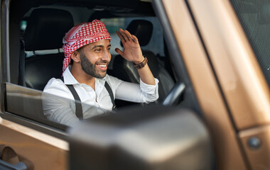 Indian arab business man wearing traditional Keffiyeh head scarf driving car