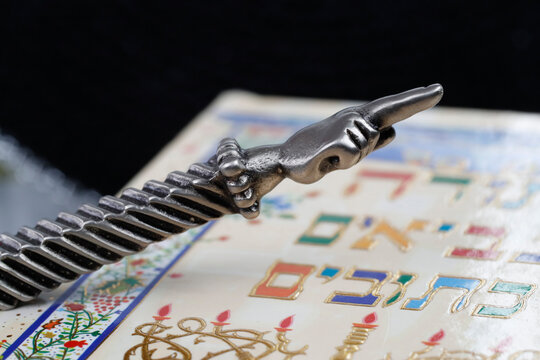 A silver Yad Jewish ritual pointer on a Torah, France