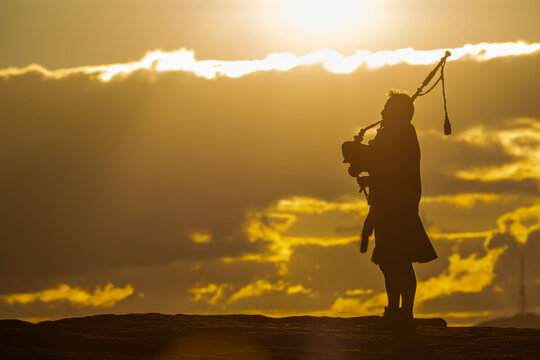 View of lone piper at at sunset on Curbar Edge, Curbar, Hope Valley, Peak District National Park, Derbyshire, England, United Kingdom