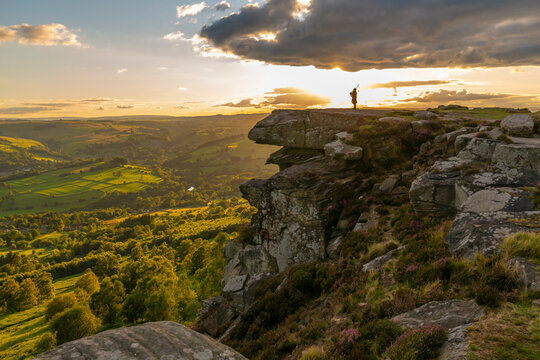 View of lone piper at at sunset on Curbar Edge, Curbar, Hope Valley, Peak District National Park, Derbyshire, England, United Kingdom