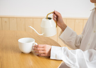 Fototapeta na wymiar a person pours tea into a white cup