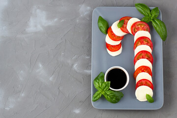 Christmas caprese salad in form of candy cane. Mozzarella and tomato on grey plate served for New year