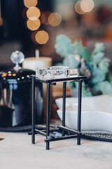 Close up of high glass candlestick on table near Christmas decoration. New Year eve concept