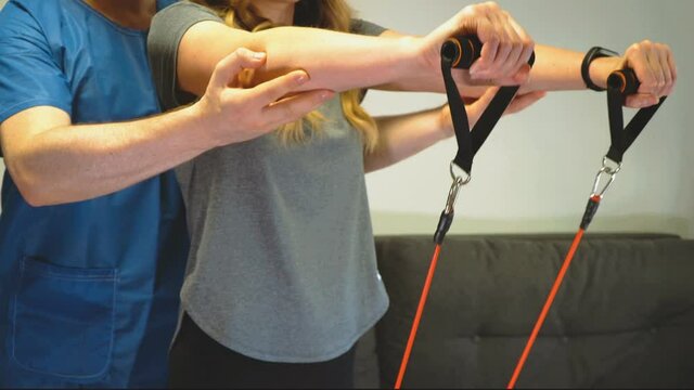 Physical therapist helping to do exercise with resistance bands. Medical homecare.