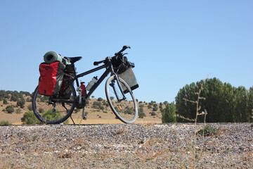 Bicycle loaded with trekking and camping equipment parked on the road in the nature outdoors.