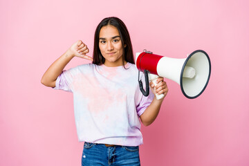 Young asian woman holding a megaphone isolated on pink background feels proud and self confident, example to follow.