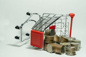 Many coins in a falling cart are caused by poor economy on white background.