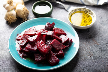 Beetroot salad with garlic and olive oil sauce in dish on dark background.