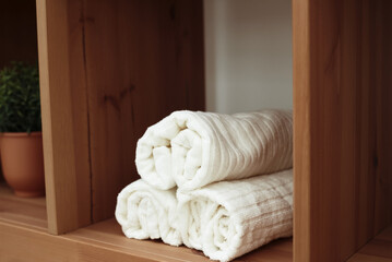 Obraz na płótnie Canvas Rolled white soft towels on shelf in bathroom
