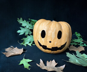Isolated Halloween pumpkin head jack lantern with autumn leaves on black background