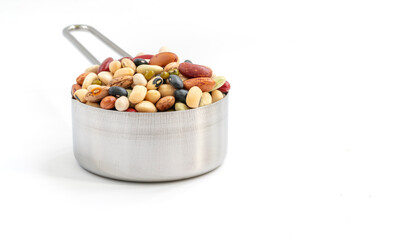 Isolated varieties of beans in stainless steel measuring cup on white background. Front view of the measuring cup.