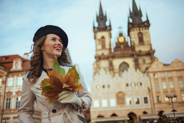 happy stylish woman in beige trench coat and black beret