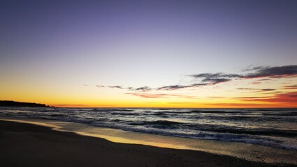 Fototapeta na wymiar Vibrant orange and yellow sky after sunset at the beach
