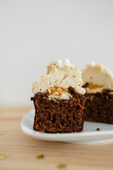 cut chocolate cupcake with caramel cream on a white saucer