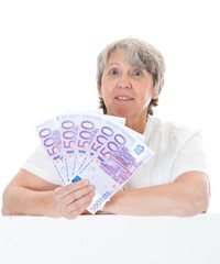 Seniorin hält Geld in die Kamera vor weißem Hintergrund
