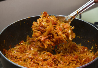 preparing homemade indian style tasty and spicy orange cabbage curry with spoon