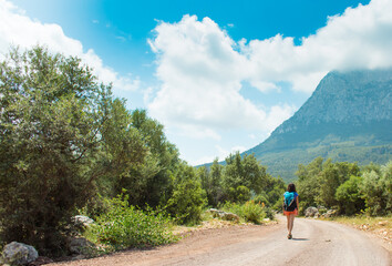 Fototapeta premium A woman with a backpack is walking along a mountain road.