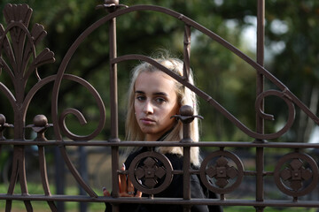 young woman behind a metal fence