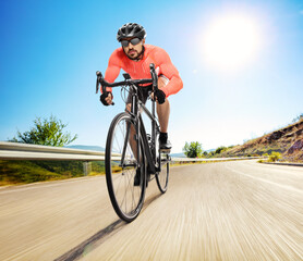 Obraz premium Male cyclist with a helmet and sunglasses riding a road bicycle on an open road
